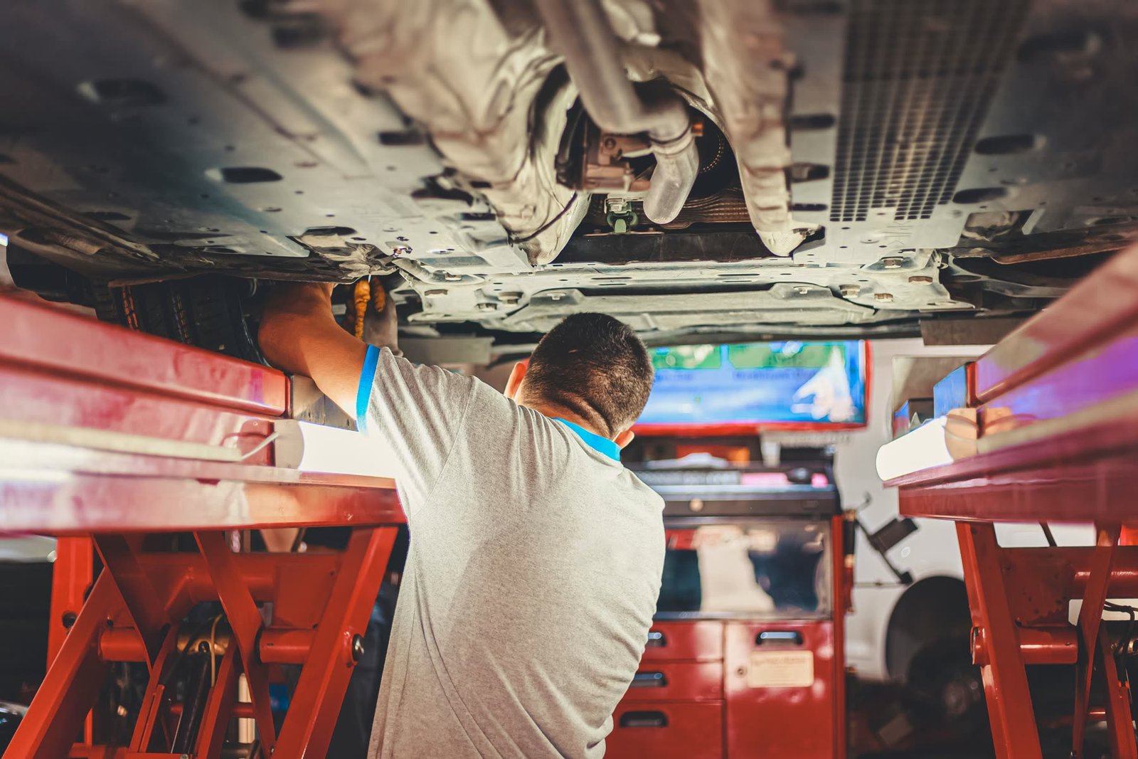 Mechanic inspecting the underside of a car on a hoist